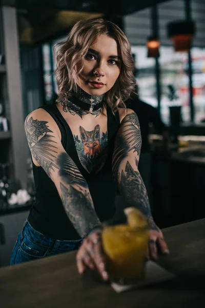 Tattooed bartender holding alcohol cocktail at bar counter — Stock Photo