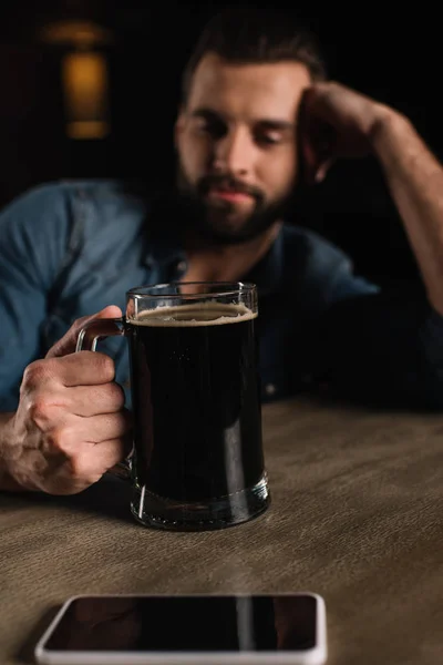 Посетитель, сидящий за стойкой бара со стаканом пива — стоковое фото