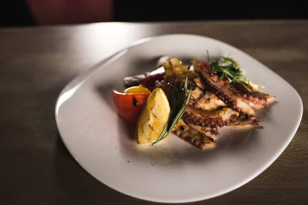 Fried vegetables and octopus on plate in cafe — Stock Photo