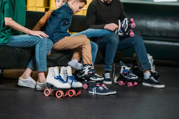Vista parcial de la familia usando patines antes de patinar en skate park - foto de stock