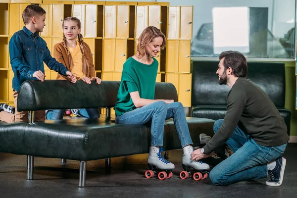 Man helping wife to wear roller skates in skate park — Stock Photo