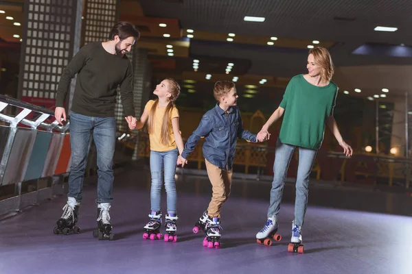 Happy family holding hands while skating together on roller rink — Stock Photo