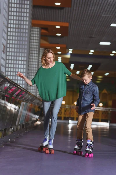 Mãe e pequeno filho patinando juntos na pista de patinagem — Fotografia de Stock