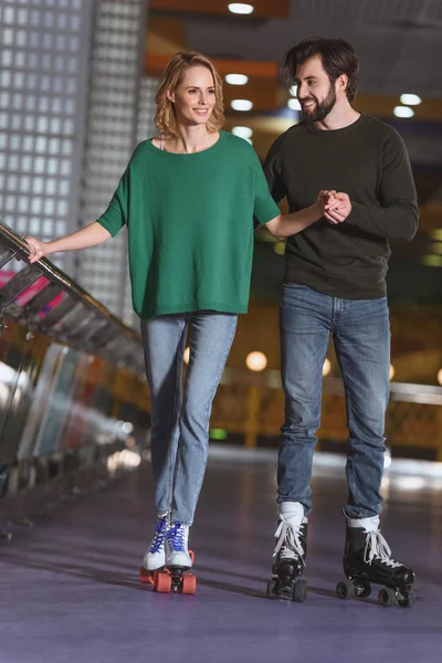 Jeune couple souriant patinant ensemble sur la patinoire — Photo de stock