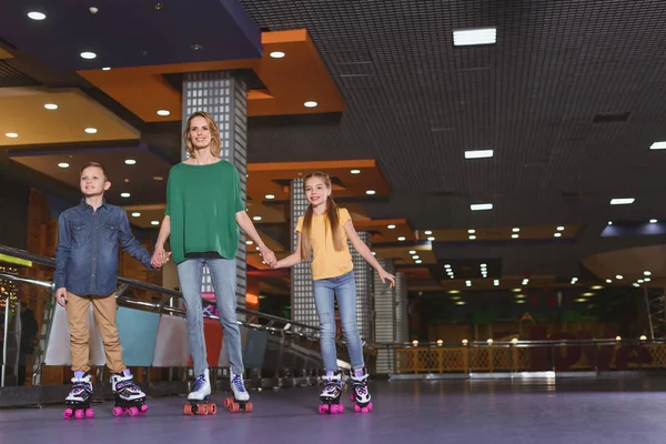 Mère et les enfants tenant la main tout en patinant ensemble sur la patinoire — Photo de stock