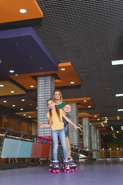 Улыбающаяся мать и дети катаются вместе на роликовых коньках — стоковое фото