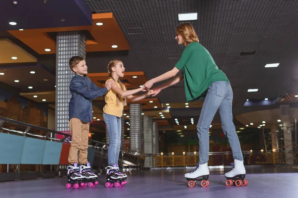 Vista lateral da mãe e crianças patinando juntos na pista de patins — Fotografia de Stock