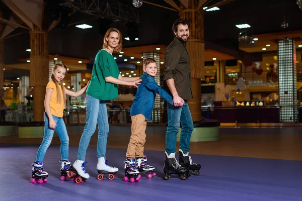 Parents and kids skating together on roller rink — Stock Photo