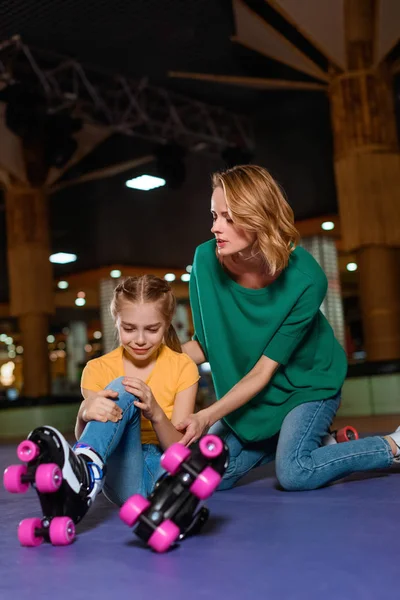 Mother cheering up crying injured daughter on roller rink — Stock Photo