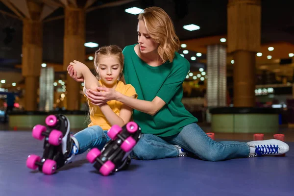 Madre animando hasta hija lesionada en pista de patinaje - foto de stock