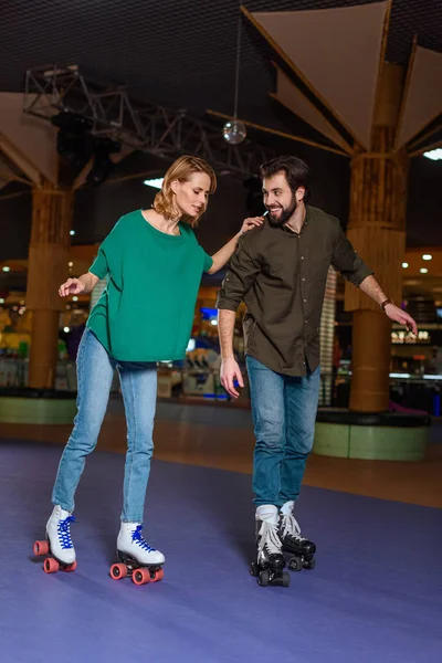 Young couple skating together on roller rink — Stock Photo