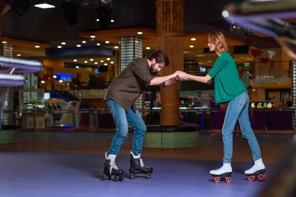 Young couple skating together on roller rink — Stock Photo