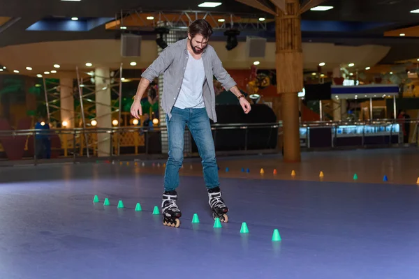Homme en patins à roulettes patiner sur la patinoire à roulettes avec des cônes — Photo de stock