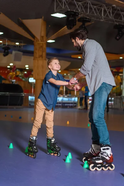 Pai e filho patinando juntos na pista de patins com cones — Fotografia de Stock
