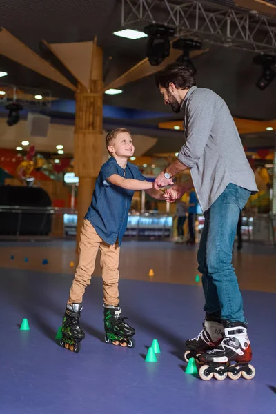 Père et fils patinant ensemble sur une patinoire à cônes — Photo de stock