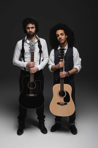 Duet of handsome young musicians with acoustic guitars on black — Stock Photo