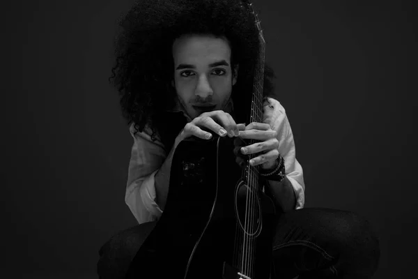 Schwarz-Weiß-Porträt eines jungen Musikers mit Akustikgitarre vor der Kamera — Stockfoto