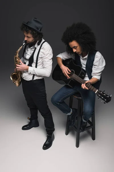 Vista de ángulo alto del dúo de músicos tocando saxo y guitarra acústica - foto de stock