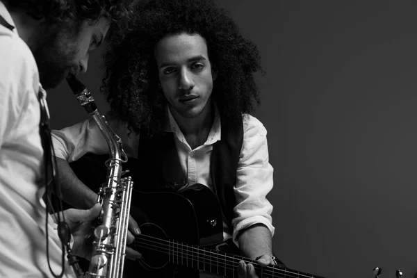 Preto e branco tiro de dueto de músicos tocando sax e guitarra acústica em preto — Fotografia de Stock