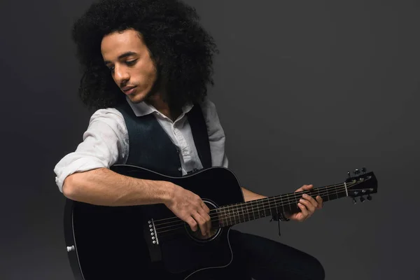 Beau jeune musicien jouant de la guitare acoustique sur noir — Photo de stock