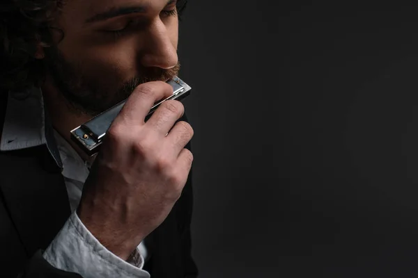 Close-up portrait of handsome musician playing harmonica on black — Stock Photo