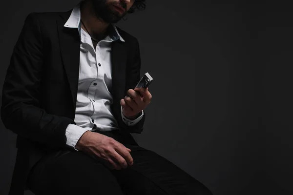 Cropped shot of man in suit holding harmonica on black — Stock Photo