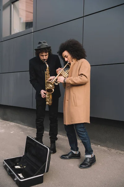 Dúo de músicos callejeros elegantes tocando trompeta y saxofón al aire libre - foto de stock