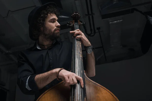 Bottom view of young handsome musician playing contrabass — Stock Photo