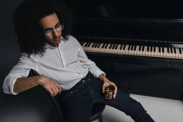 Musicista afroamericano con bicchiere di whisky davanti al pianoforte — Foto stock