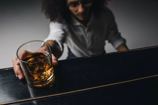 Giovane che suona il pianoforte e raggiunge per un bicchiere di whisky — Foto stock