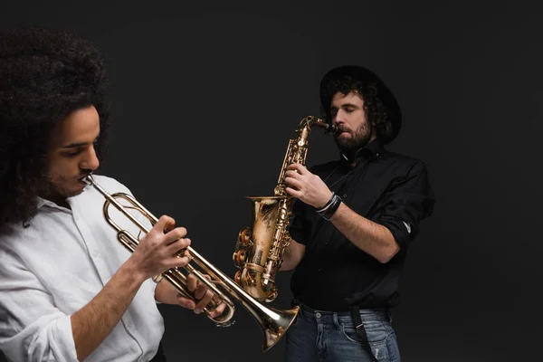 Duet of musicians playing trumpet and saxophone on black — Stock Photo