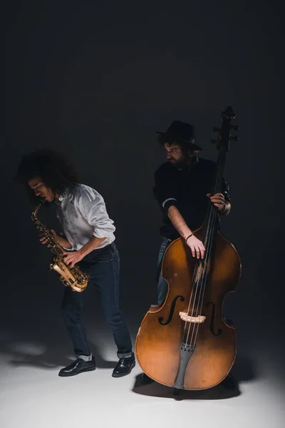 Dueto de jazzmen tocando trompeta y saxofón en negro - foto de stock