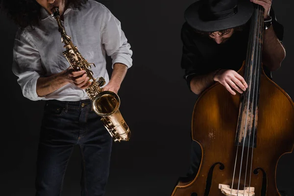 Dueto de jazzmen tocan violonchelo y saxo en negro - foto de stock
