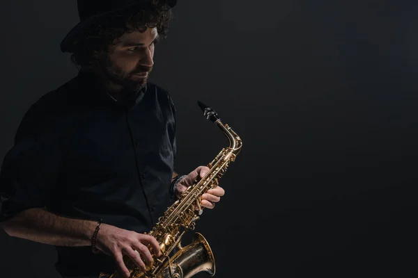 Jovem músico tocando saxofone no preto — Fotografia de Stock