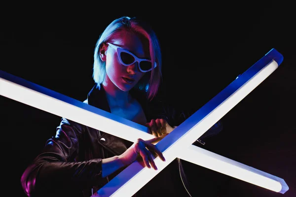 Attractive girl posing with two ultra violet lamps for fashion shoot, isolated on black — Stock Photo