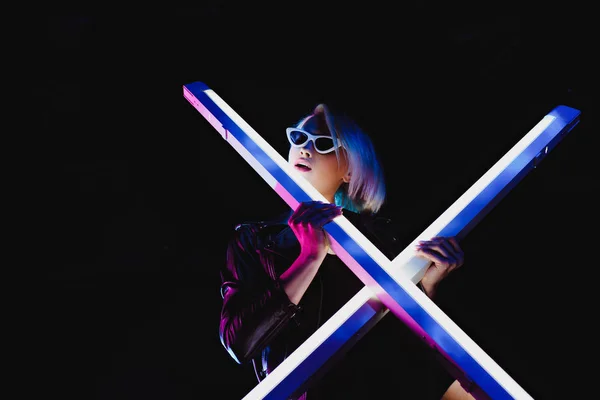 Fashionable girl posing with two ultra violet lamps, isolated on black — Stock Photo