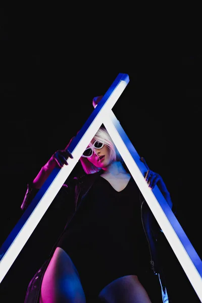 Modèle élégant posant avec deux lampes ultraviolettes pour le tournage de mode, isolé sur noir — Photo de stock