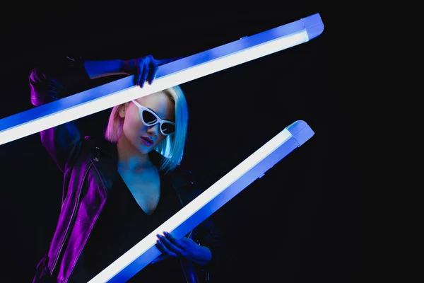 Fashionable model posing with two ultraviolet lamps, isolated on black — Stock Photo