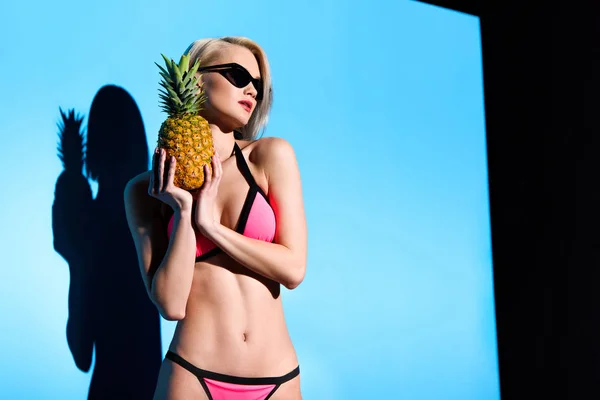 Красивая девушка позирует в бикини с ананасом для модной съемки — стоковое фото