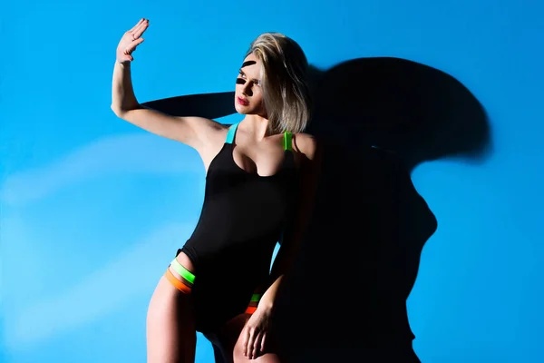 Beautiful blonde girl gesturing and posing in swimsuit, on blue — Stock Photo