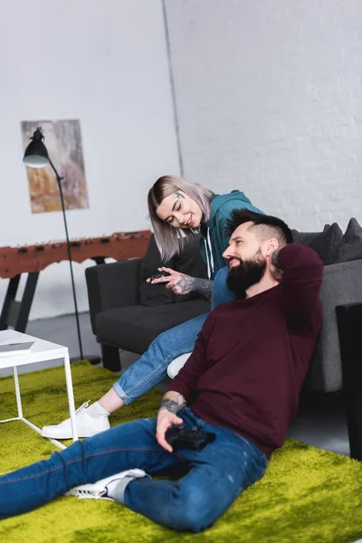 Tattooed couple playing video game in living room — Stock Photo