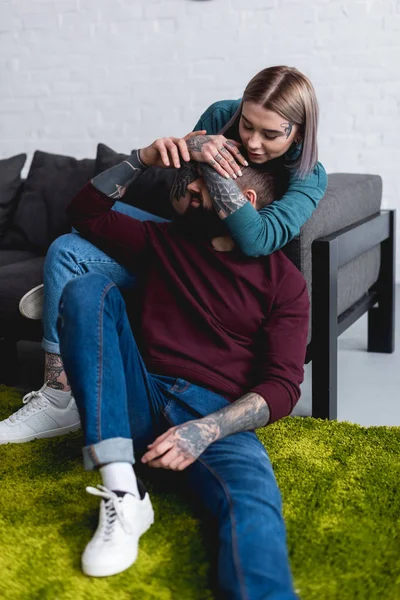 Happy tattooed girlfriend covering boyfriends eyes in living room — Stock Photo