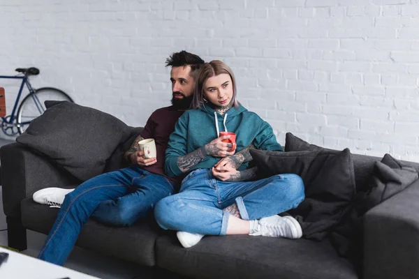 Tätowiertes Paar mit Tassen Kaffee zu Hause — Stockfoto