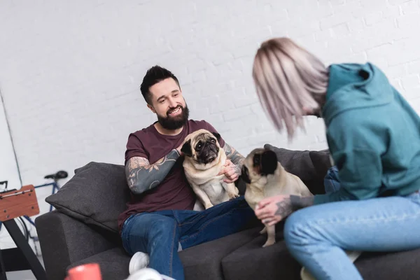 Happy tattooed couple with dogs on sofa at home — Stock Photo