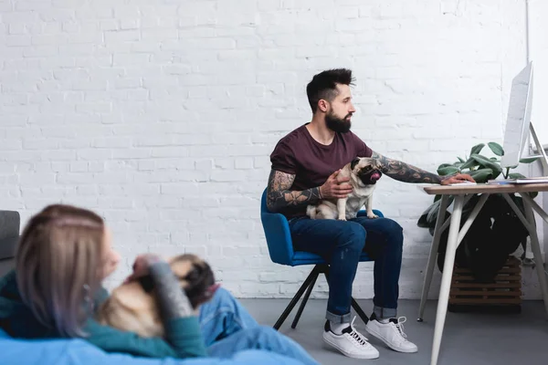 Tattooed couple with cute pugs at home — Stock Photo