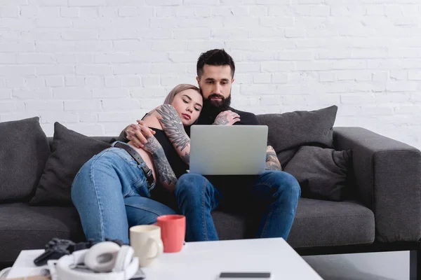 Tattooed couple hugging and watching movie together at home — Stock Photo