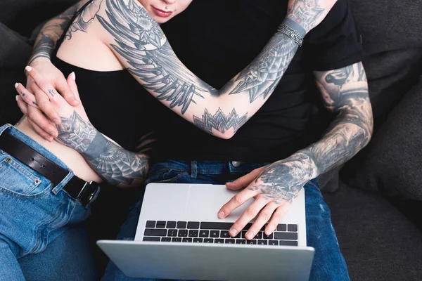 Imagen recortada de pareja tatuada utilizando el ordenador portátil - foto de stock