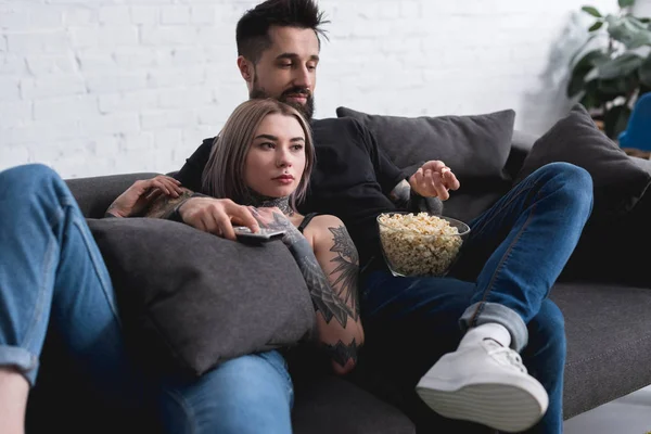 Tätowiertes Paar schaut Film mit Popcorn zu Hause — Stockfoto