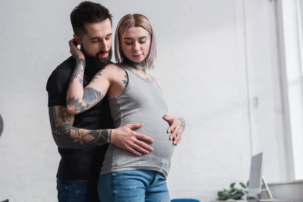 Tatoué copain câlin petite amie enceinte de retour à la maison — Stock Photo