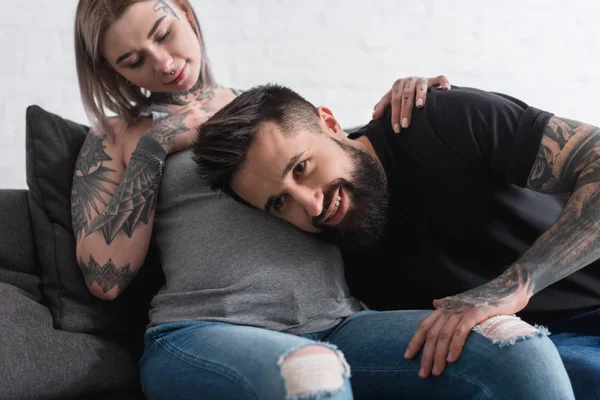 Novio tatuado escuchando abdomen de novia embarazada en casa - foto de stock